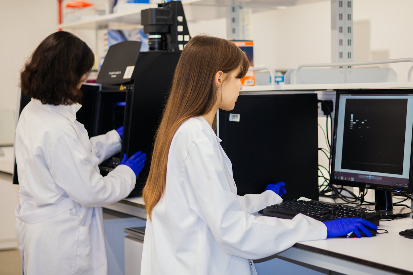 Ricercatori collaborano in un laboratorio moderno usando macchinari scientifici e computer.