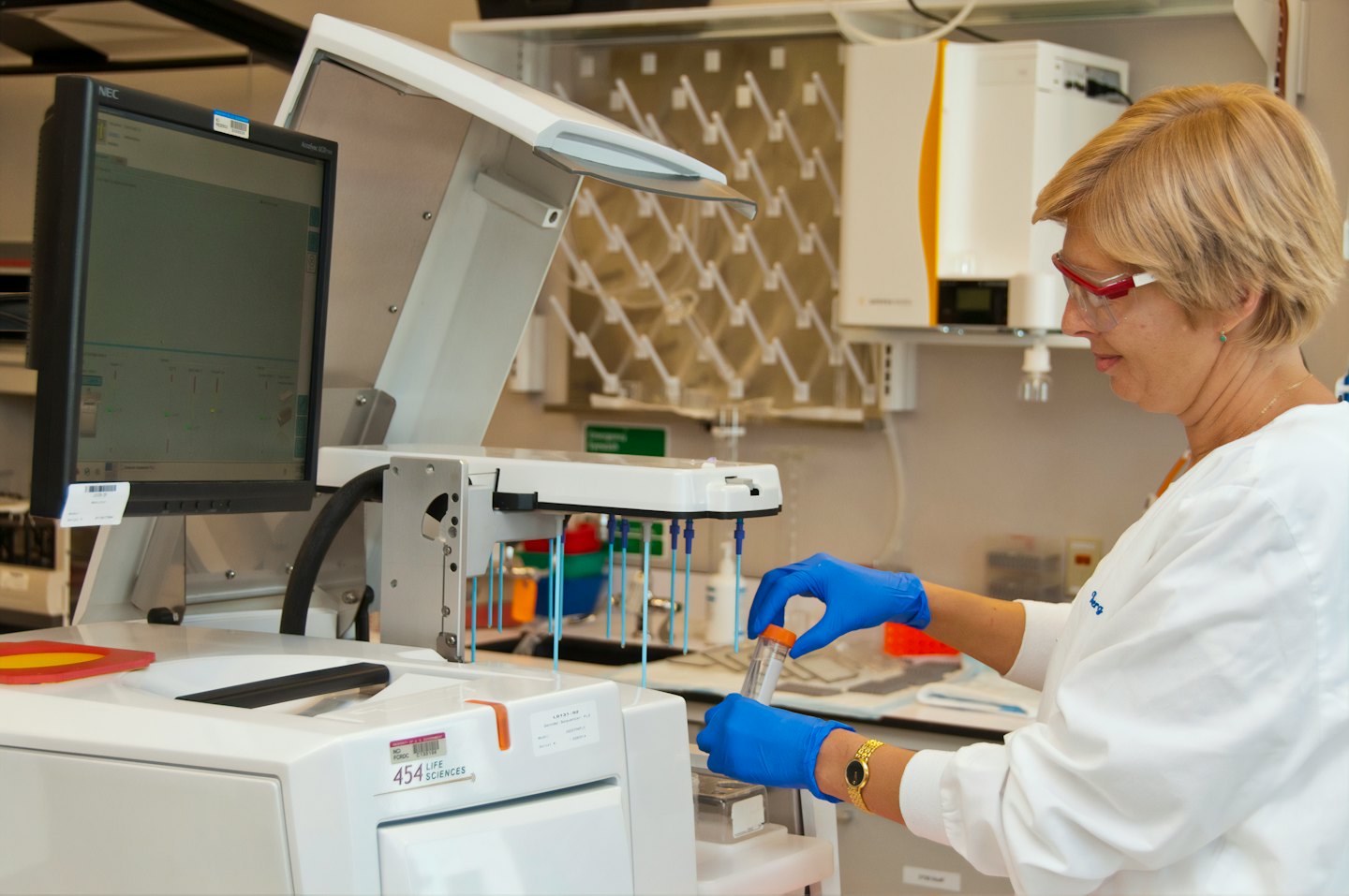 Scienziato in camice da laboratorio esamina una provetta con attrezzature.