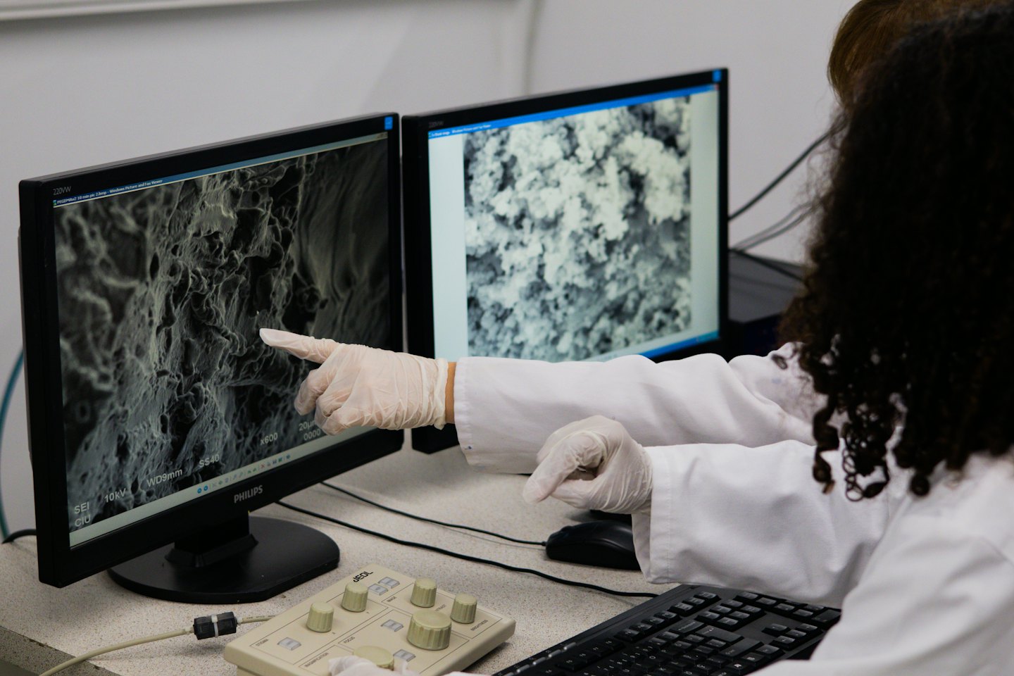 Ricercatore analizza immagine al microscopio elettronico su monitor in laboratorio.